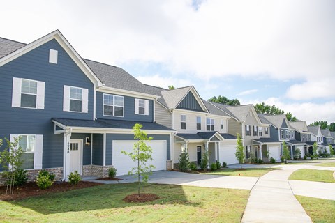 a row of blue houses with white doors and a sidewalk