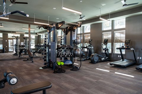 A gym with a variety of equipment including treadmills, weights, and exercise machines.