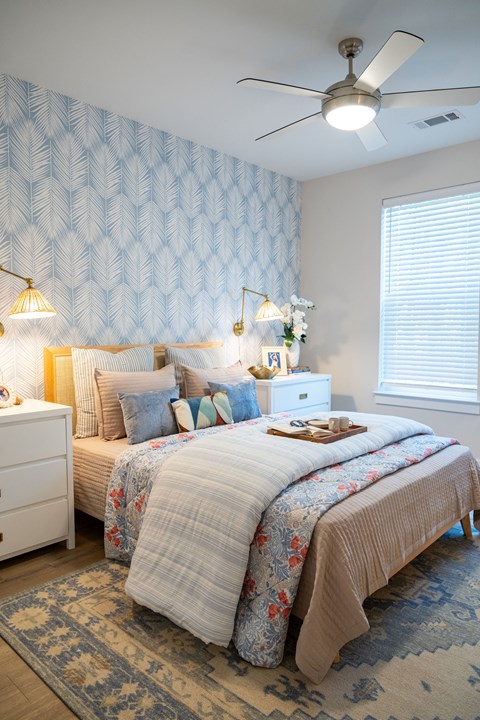 A bedroom with a bed, nightstand, and ceiling fan.