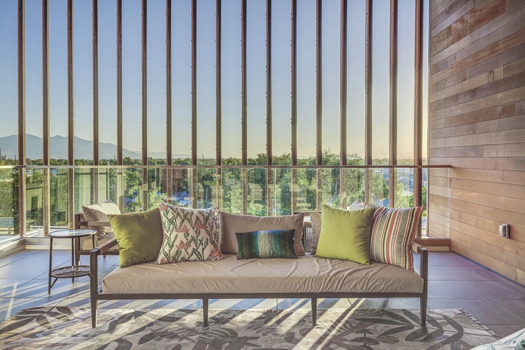 a couch with pillows in front of a window with vertical blinds