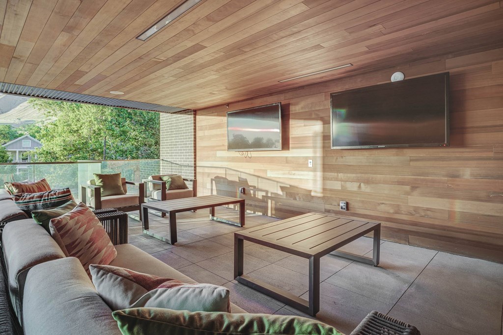 a covered patio with a couch coffee table and tv