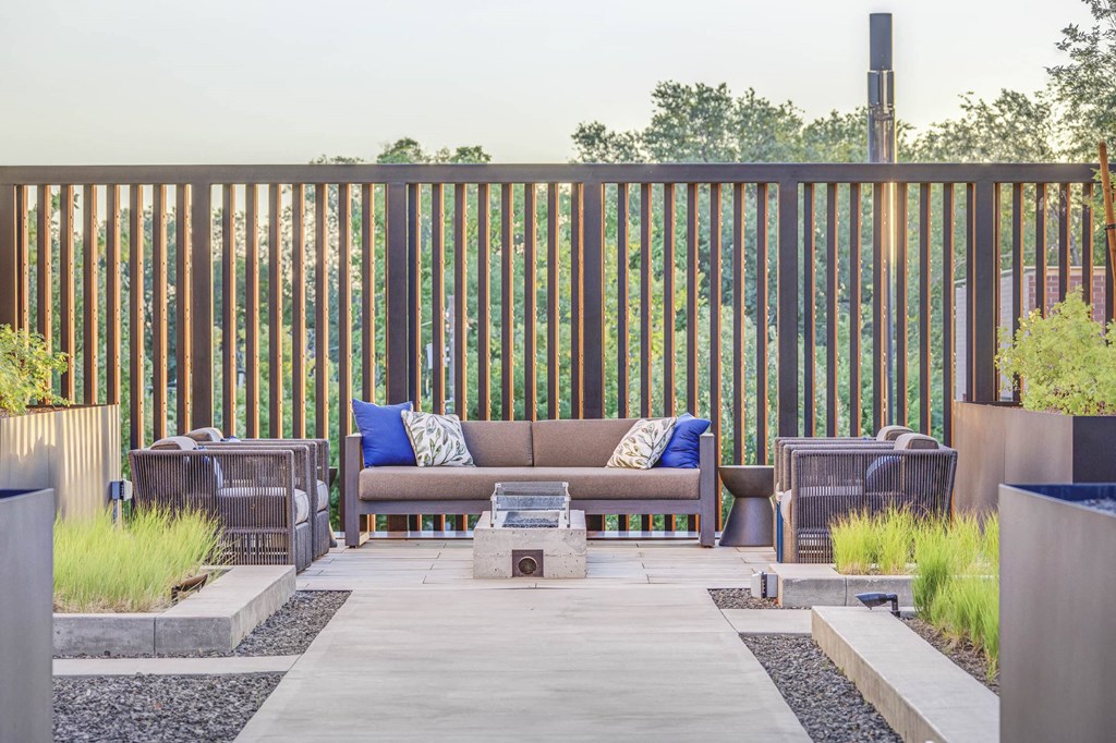 a patio with a couch and chairs with a fire pit in the middle