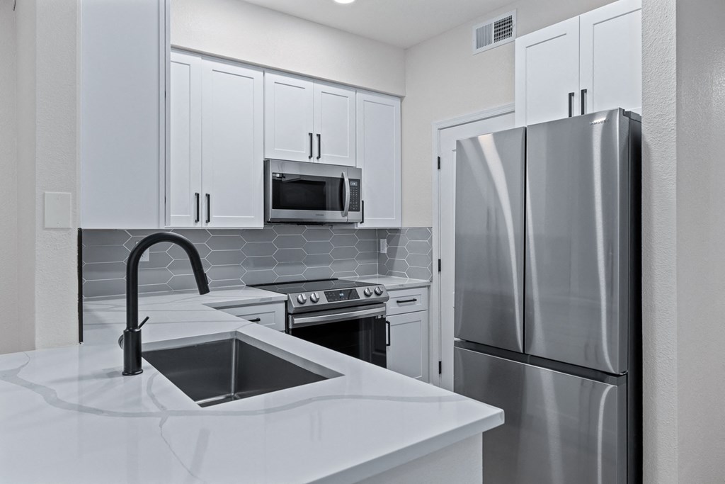 a kitchen with white cabinets and stainless steel appliances