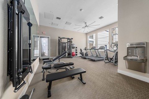 A gym with a variety of equipment including a treadmill, weights, and a bench.