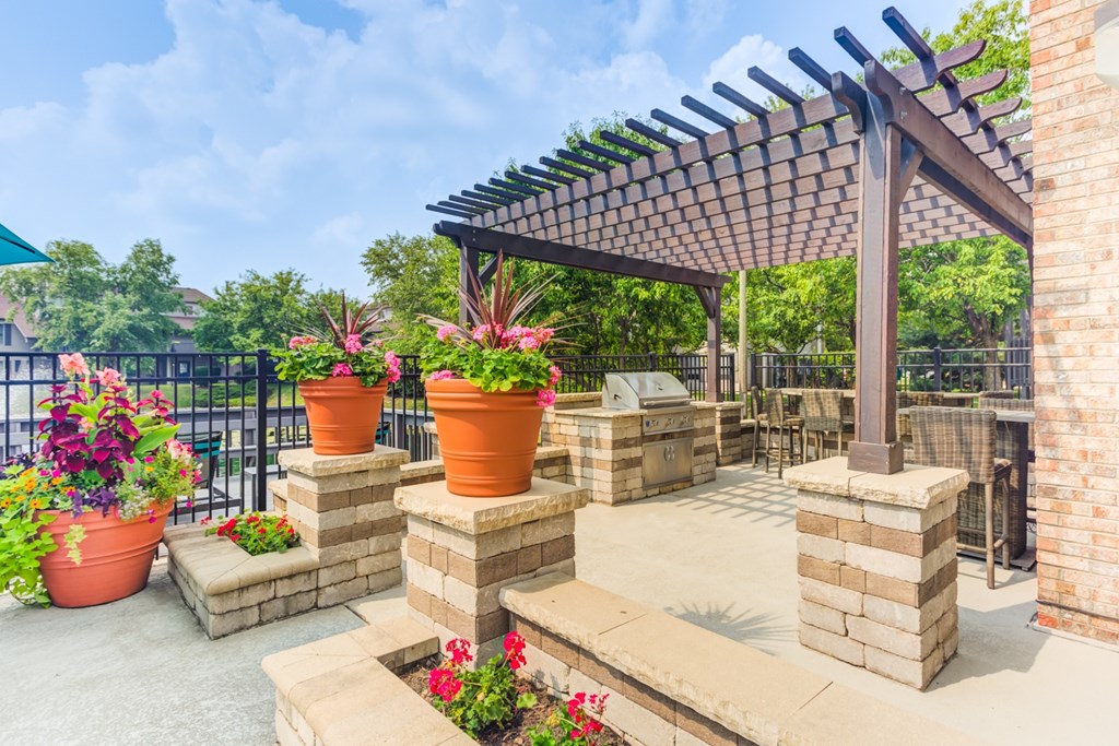 A patio with a pergola and flower pots.