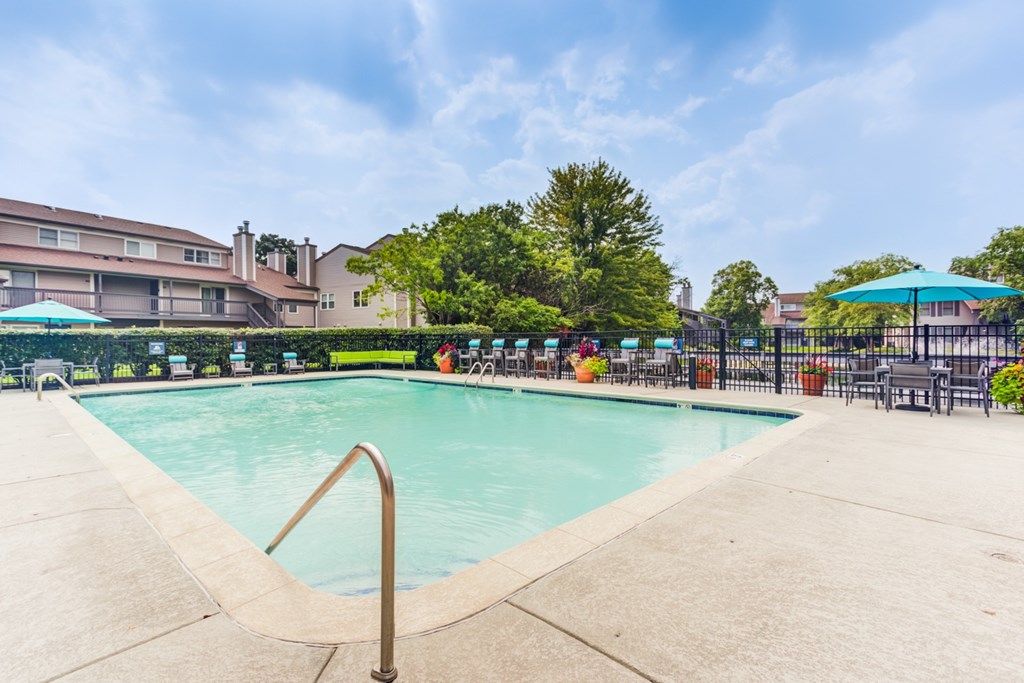 A swimming pool surrounded by a concrete patio and a metal fence.