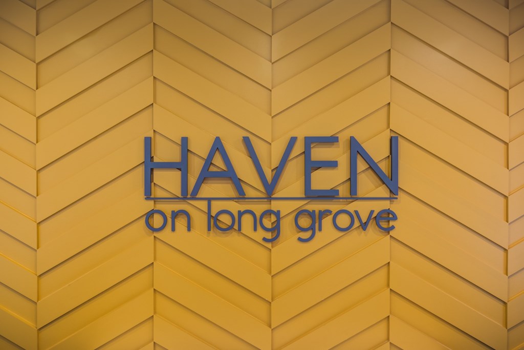 A sign that says Haven on Long Grove is displayed on a yellow wall.