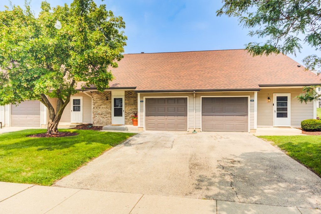 A house with a brown roof and a tree in front.