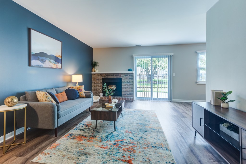 A living room with a grey couch, a coffee table, and a large window.