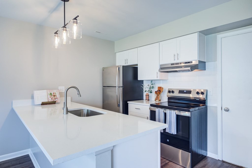 A modern kitchen with a white countertop and stainless steel appliances.