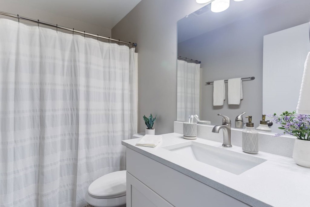 A white bathroom with a toilet, sink, and shower curtain.