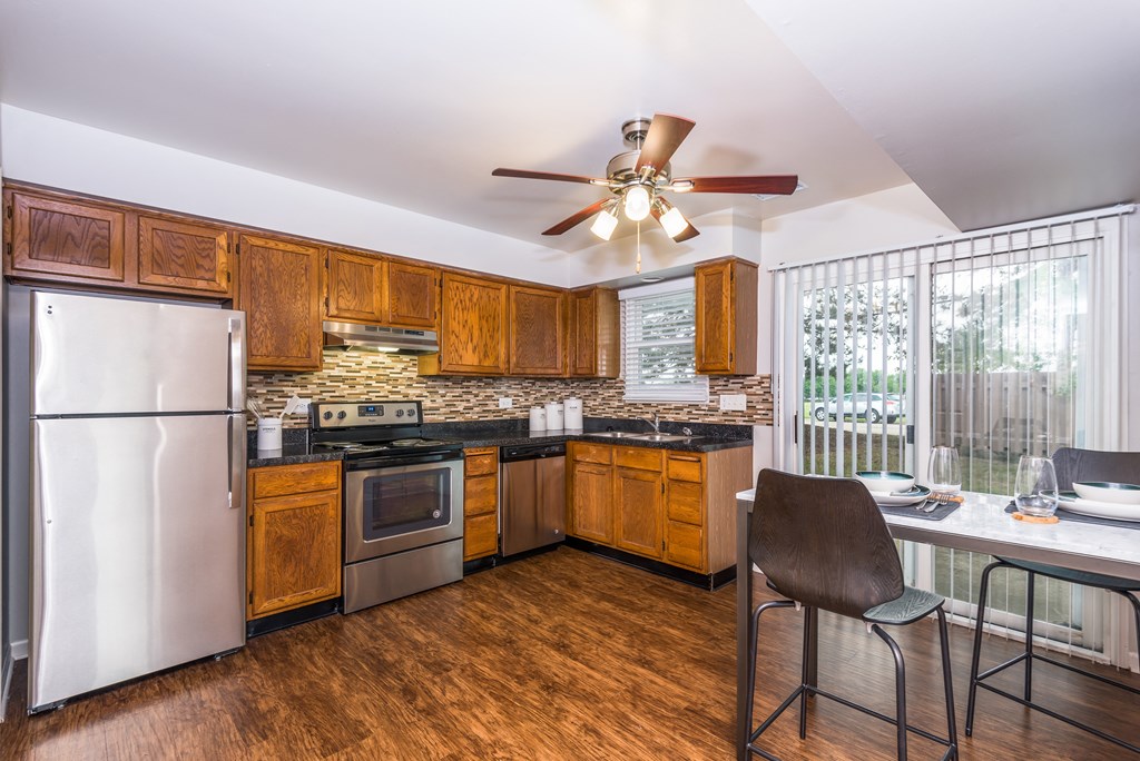 a kitchen with wooden cabinets and stainless steel appliances and a ceiling fan