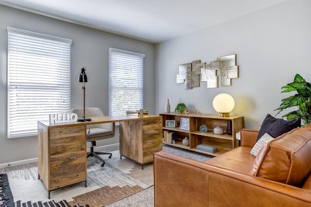 a home office with a leather couch and a wooden desk