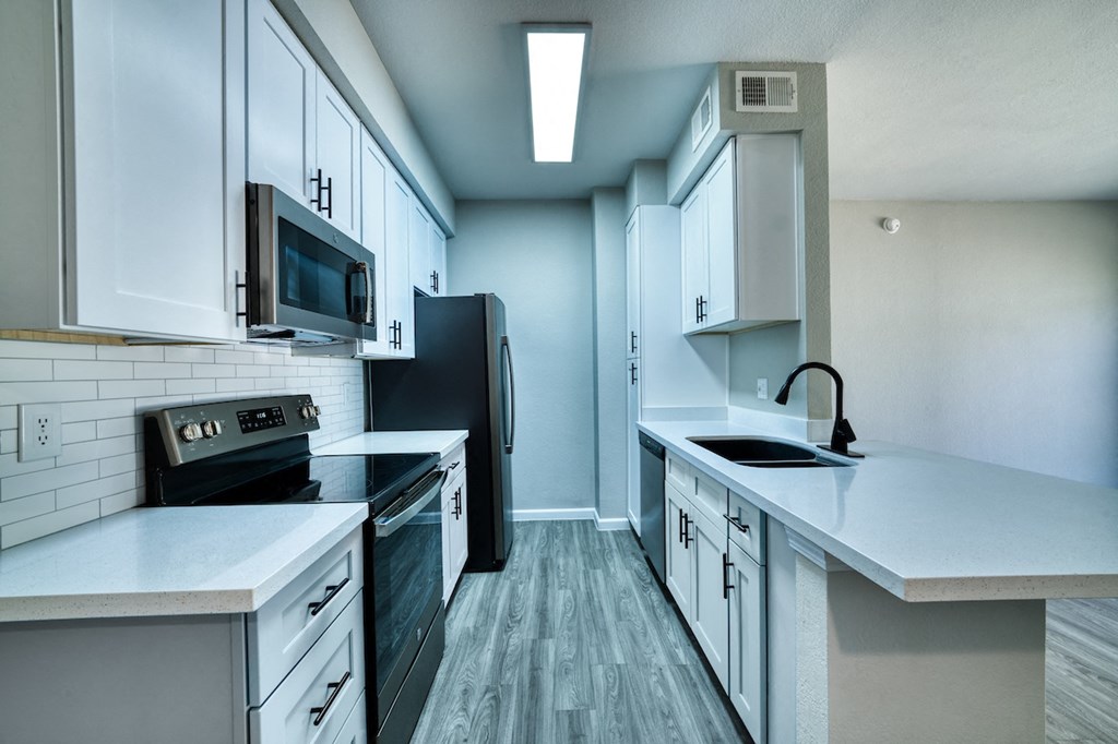 a kitchen with white cabinets and black appliances