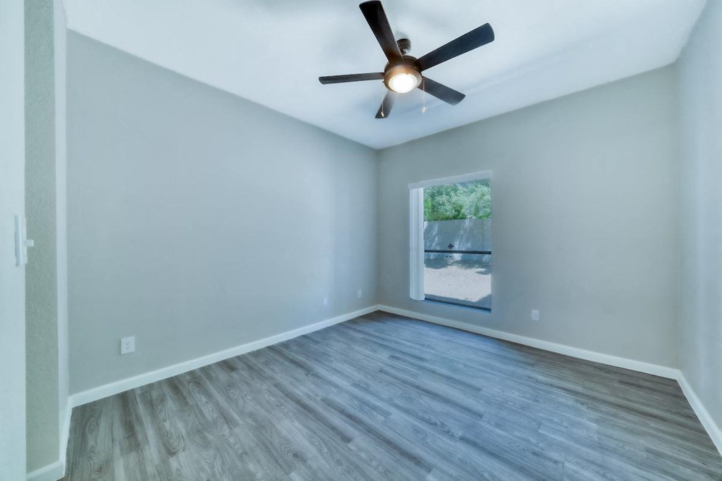 an empty room with a ceiling fan and a window