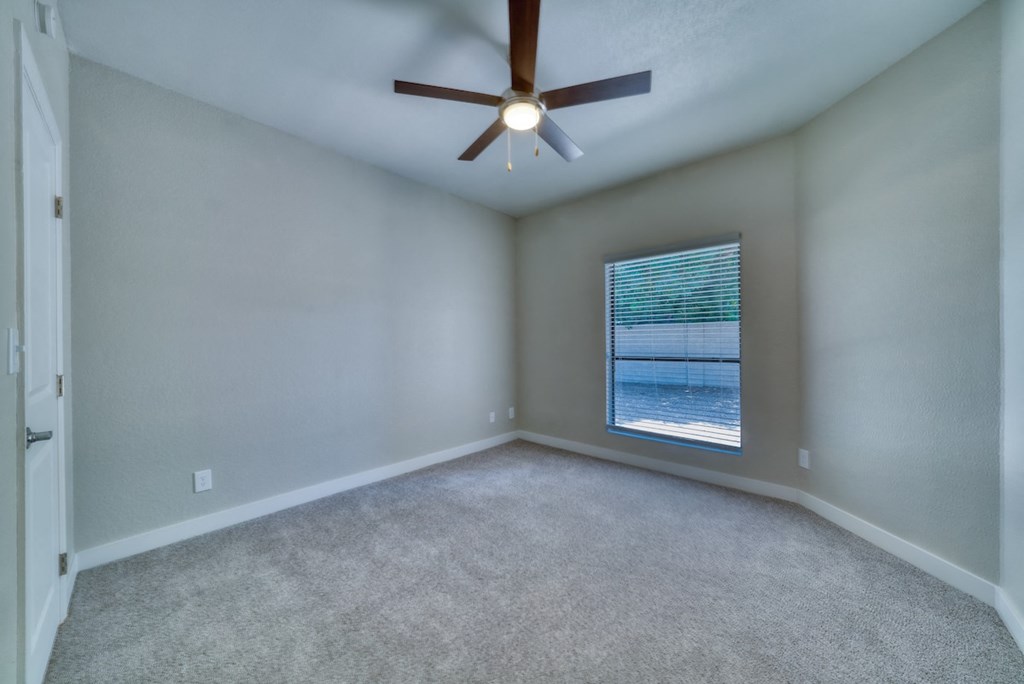 an empty room with a ceiling fan and a window