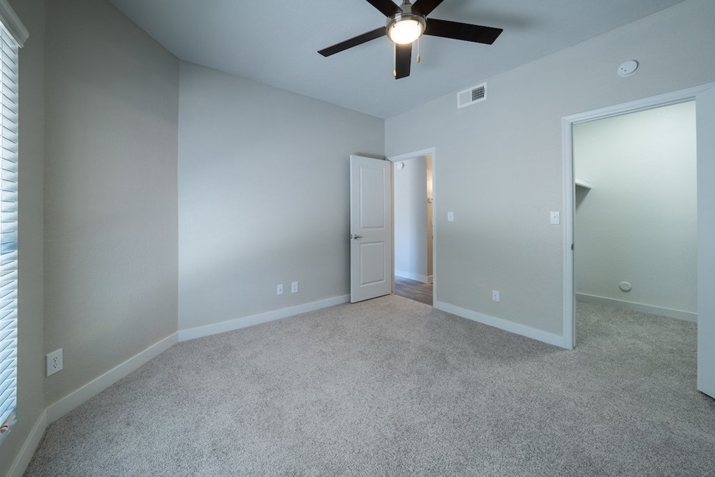 a bedroom with gray walls and a ceiling fan