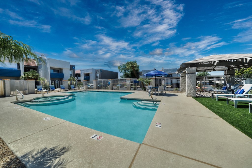 a resort style pool with lounge chairs and umbrellas