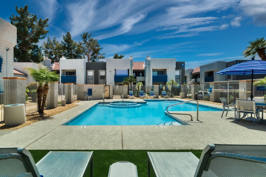 a swimming pool with lounge chairs and umbrellas at the whispering winds apartments in pearland
