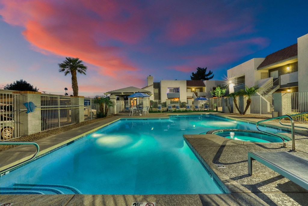 a swimming pool with a colorful sunset in the background
