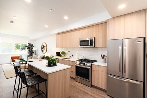 a kitchen and living room with stainless steel appliances and wooden cabinets