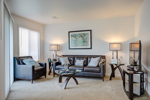 A living room with a grey couch, a black chair, a coffee table, and a painting on the wall.