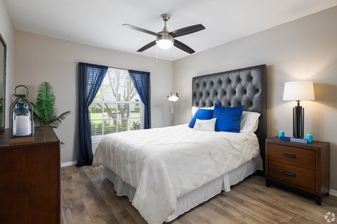 A bedroom with a white bed and a ceiling fan.