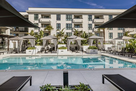 a swimming pool with umbrellas and a building in the background