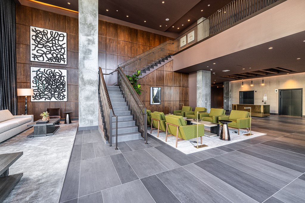 a lobby of a hotel with a staircase and chairs and tables