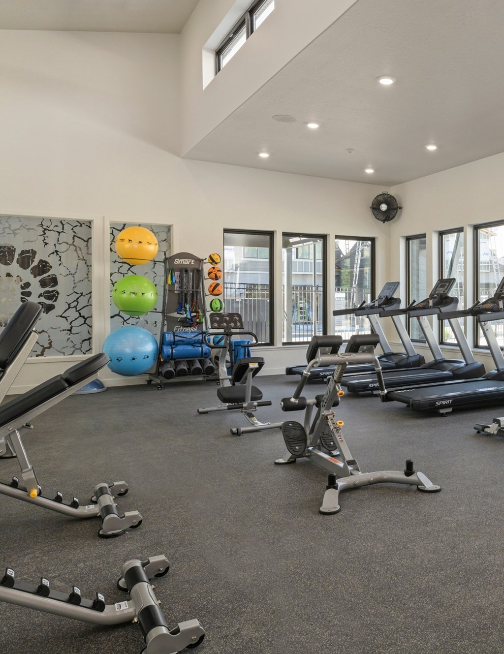 A gym with a variety of equipment including treadmills, exercise balls, and weight machines.