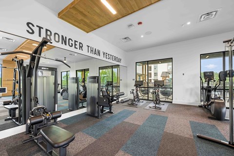 A gym with a variety of equipment and a sign that says "STRONGER THAN YESTERDAY".