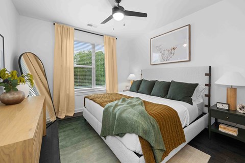 A bedroom with a bed, nightstand, and a ceiling fan.