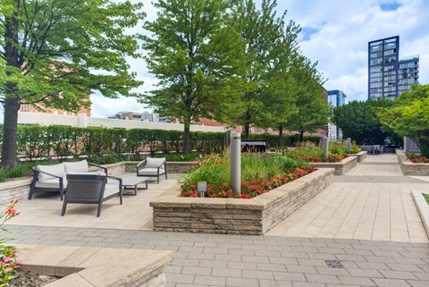 A park with a stone planter in the middle of a paved walkway.
