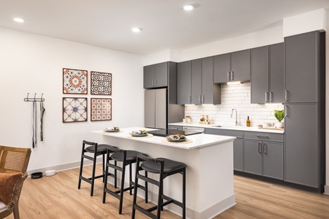 A kitchen with a white counter and black bar stools.