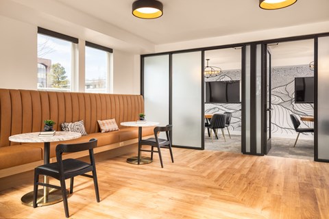 a lounge area with tables and chairs and a television with private work room