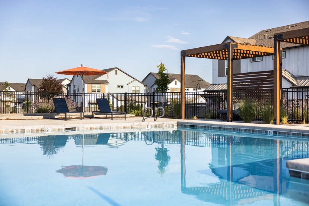 A pool with a red umbrella and a black fence.