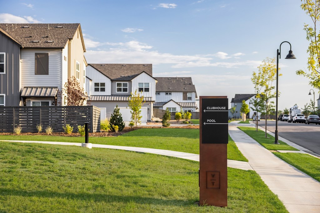 A signpost in a grassy area in front of a row of houses.
