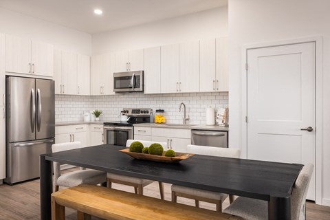 A kitchen with a black table and a bowl of fruit on it.