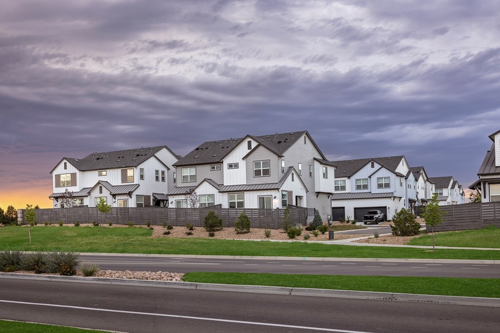 A row of houses with a car parked in the driveway.