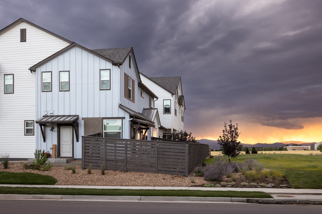 A white house with a grey fence in front of it.