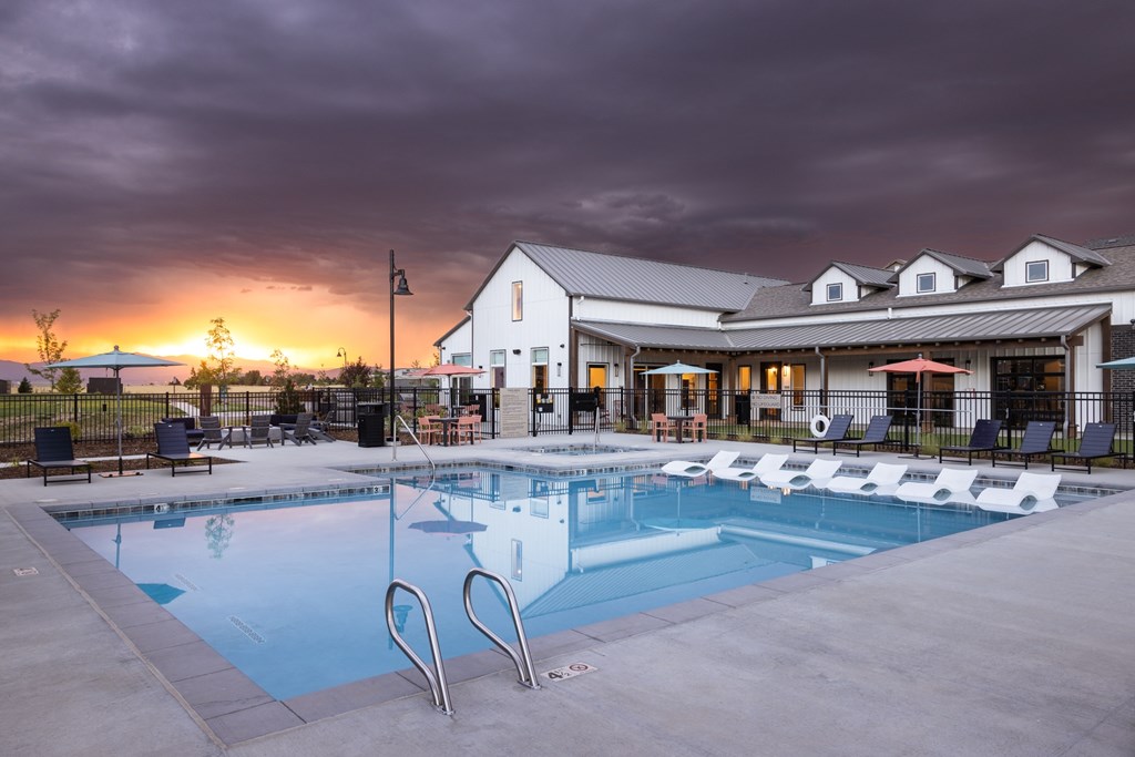 A swimming pool in front of a building with a sunset in the background.