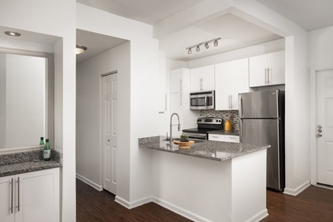 A kitchen with white cabinets and a granite countertop.