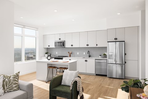 A modern kitchen with a green chair and a grey couch.