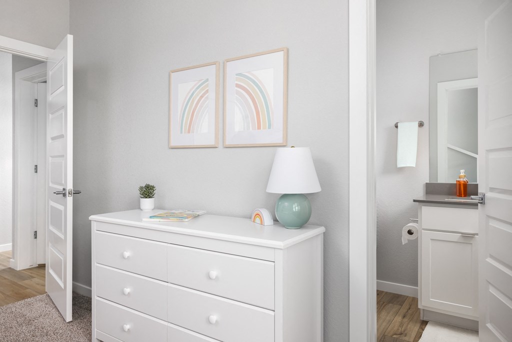 a bedroom with a white dresser and a lamp and a closet