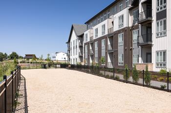 Apartment complex with a sandy courtyard in front.