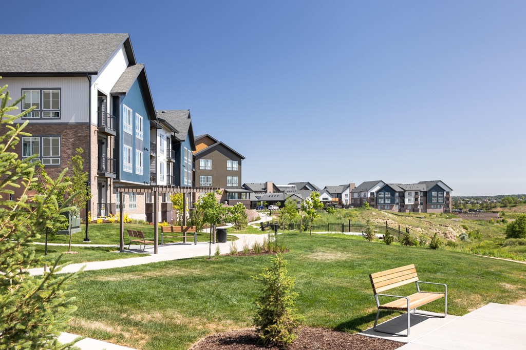 A park with a bench and a building in the background.