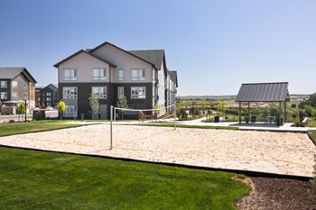 A sand volleyball court is located in front of a building.