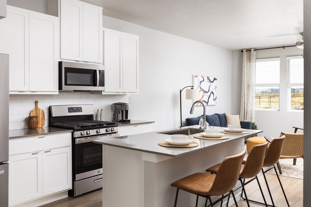 an open kitchen and dining area with white cabinets and a table with chairs