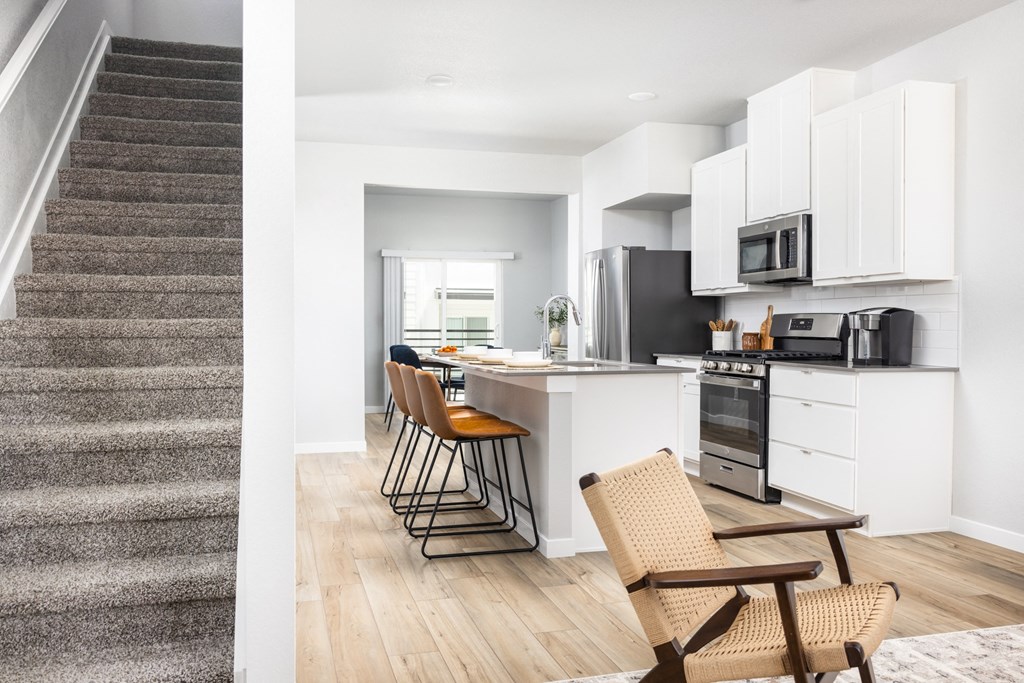 an open kitchen and dining area with a stairwell and a kitchen counter with chairs
