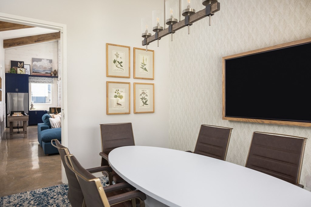 a dining room with a white table and chairs and a television on the wall